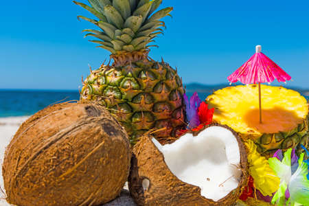 Coconuts and pineapples on the beach in summerの写真素材