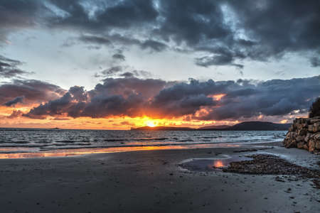 Shining sun and dark clouds at sunset. Sardinia, Italyの写真素材