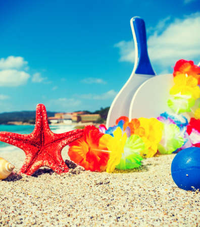 Star fish and beach rackets on the sand in summertimeの写真素材