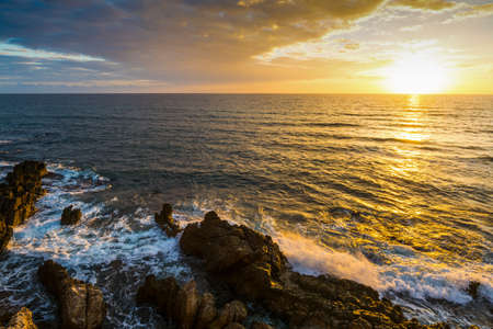 Rocky shore under a bright sun at sunset. Alghero, Italyの写真素材