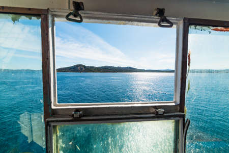 Blue sea in Sardinia seen through a ferry boat window, Italyの写真素材