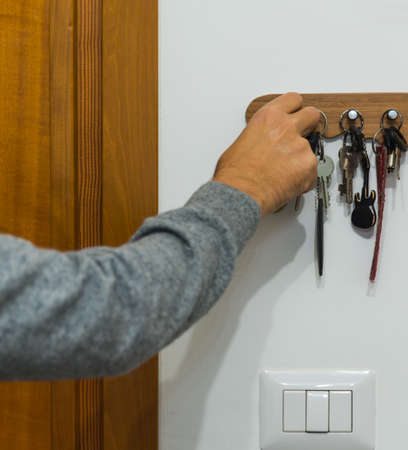 Man grabbing a key from the key holderの写真素材