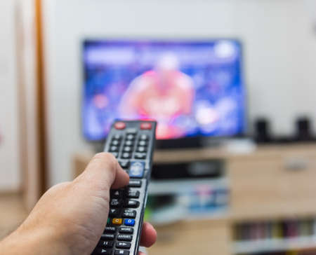 Close up of a man surfing the channels の写真素材