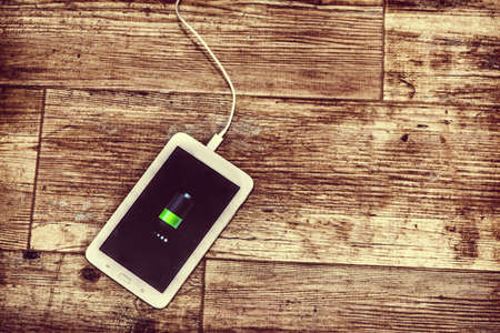 Tablet charging on a wooden floor in vintage effectの写真素材
