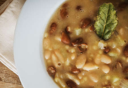 White plate with fregola and beans soup on a wooden tableの写真素材