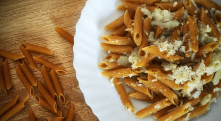 Whole wheat pasta and cauliflower on a wooden table seen from aboveの写真素材