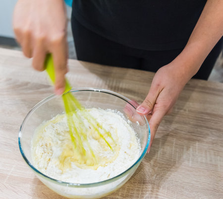 Close up of a cook stirring a cake dough in a bowl