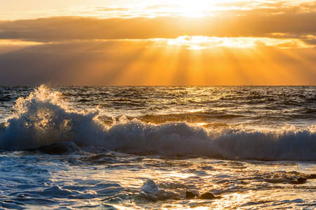 Wave under an orange sun at sunset. Sardinia, Italyの写真素材