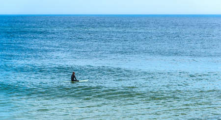 Surfer sitting on his surfboard waiting for the waves in Florida, USAの写真素材