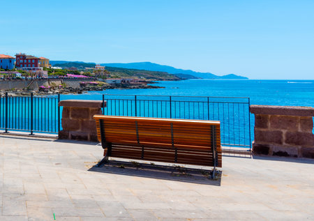 Wooden bench in Alghero seafront on a clear day. Sardinia, Italy