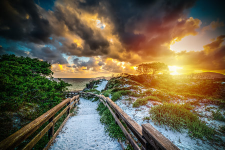Wooden handrail in Maria Pia beach at sunset. Sardinia, Italy