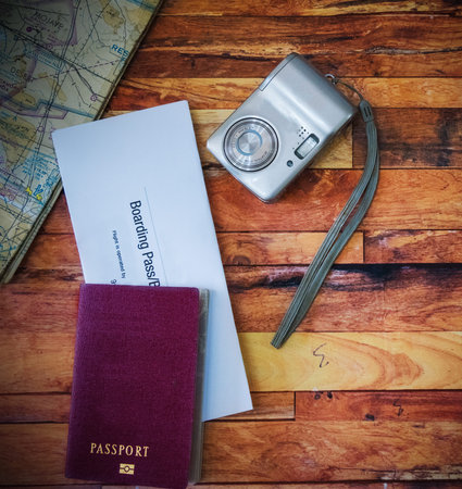 Passport, boarding pass, camera, map on a wooden table
