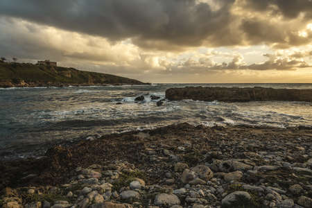 Rocky shore under a cloudy sky at sunset. Alghero, Italyの写真素材