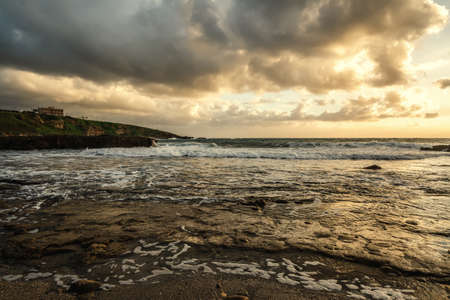 Dark clouds over Alghero rocky shore at sunset. Sardinia, Italyの写真素材