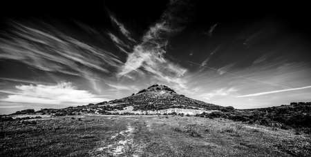Small hill under a cloudy sky in Sardinia, Italy. Black and white effectの写真素材
