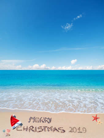 santa hat and "merry Christmas 2019" written on a tropical beachの写真素材