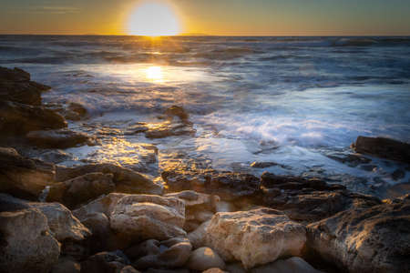 Rocky shore under a shining sun at sunset. Sardinia, Italyの写真素材