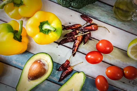 Avocado, bell peppers, tomatoes, chili peppers, broccoli and olive oil seen from aboveの写真素材