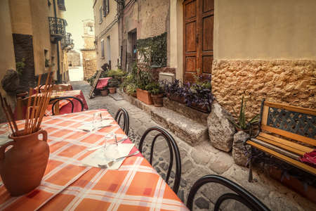 Tables and chairs in a narrow alley in old town Castelsardo. Sardinia, Italyの写真素材