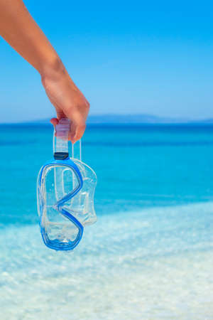 Girl holding a scuba mask by the sea in the summertimeの写真素材