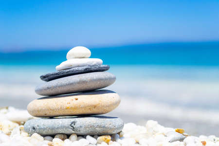 Pile of stones on white pebbles by the sea in summerの写真素材
