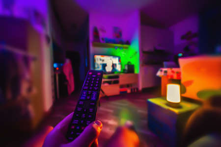 Man watching tv in a colorful living room at nightの写真素材
