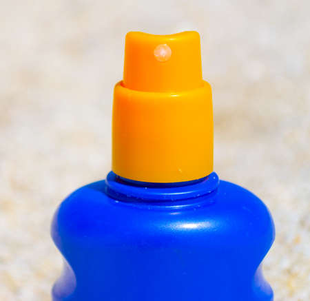Extreme close up of a blue and yellow suntan bottle on a white beachの写真素材