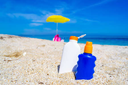 Blue and white suntan bottles on a white beach in the summertimeの写真素材
