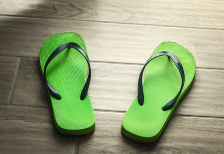 Detail of green flip flops on a grey floor の写真素材