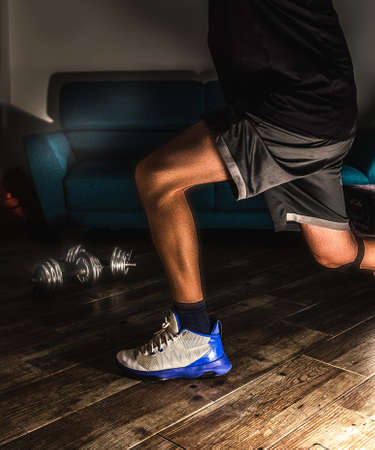 Man doing lunges in the living room during home workoutの写真素材