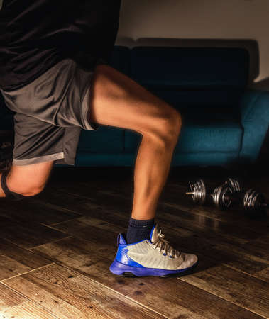 Side view of a man doing lunges during home workoutの写真素材