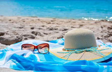 Sunglasses and beach hat on the sand in summertimeの写真素材