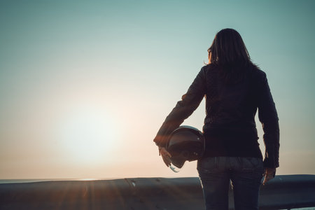Biker girl with helmet looking at the sunset
