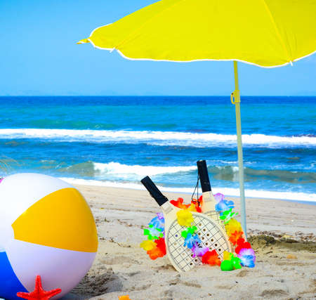 Beach rackets and other summer objects on the sand by the seaの写真素材