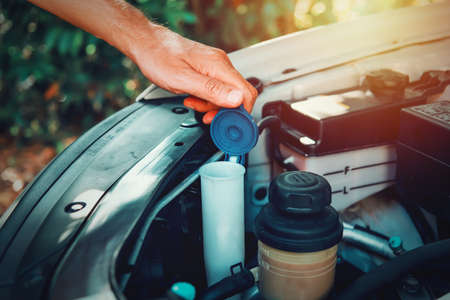 Close up of a man opening the windshield washer fluid tank of an suvの写真素材