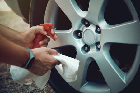 Close up of a man with towel and spray bottle about to wash car wheelsの写真素材