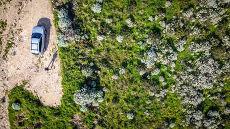 Man by a car in the countryside seen from above in springtimeの写真素材