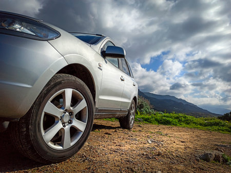 Grey SUV parked on a dirt road under a dramatic sky. Sardinia, Italy