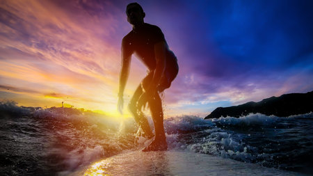 Surfing at sunset under a colorful sky