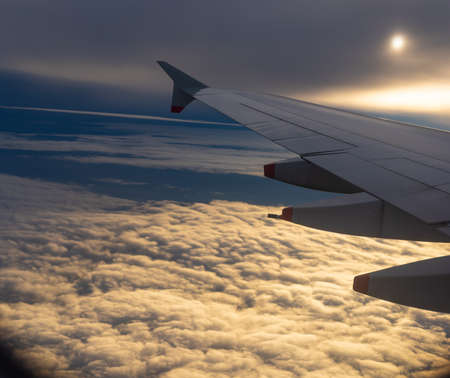 Commercial airplane flying over a carpet of clouds at sunsetの写真素材
