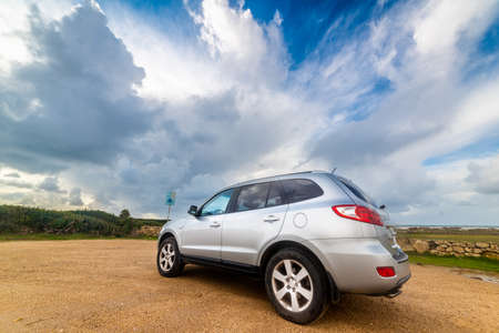Grey SUV under a dramatic sky in Sardinia, Italyの写真素材