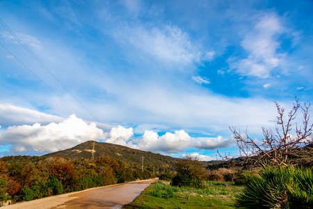 Country road among the hills under a blue sky with clouds. Sardinia, Italyの写真素材