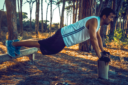 Man doing push ups in a park at sunset