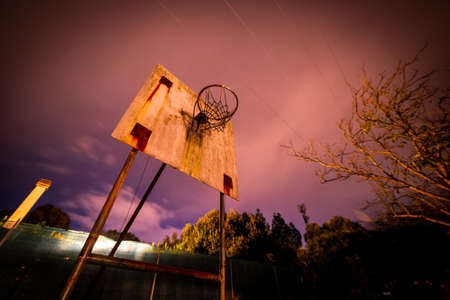 Old Basketball hoop in a backyard at nightの写真素材