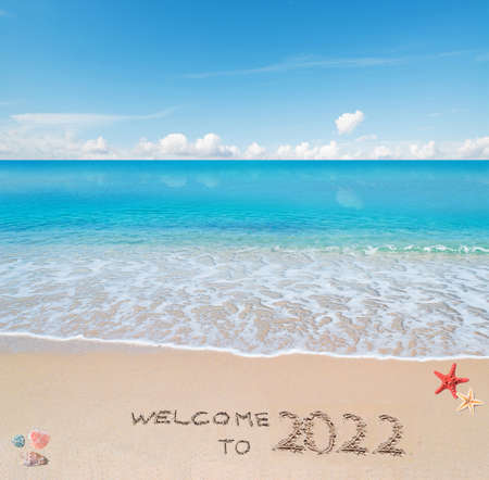 turquoise water and golden sand with shells and sea stars with "welcome to 2022" written on itの写真素材