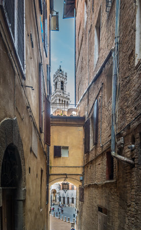 Narrow alley in Siena under a blue sky with clouds. Tuscany, Italyの写真素材
