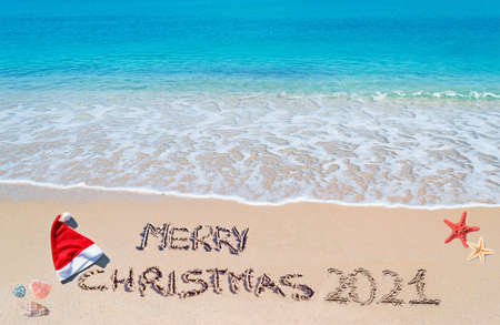 santa hat and "merry Christmas 2021" written on a tropical beachの写真素材