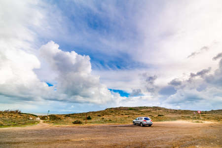 Grey SUV parked by the sea under a cloudy sky in Sardinia, Italyのeditorial素材