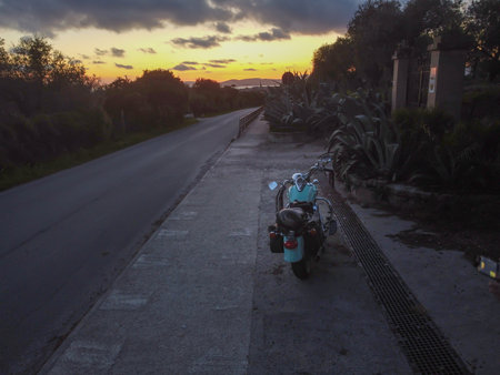Classic motorcycle parked on the edge of a country road at sunsetの写真素材