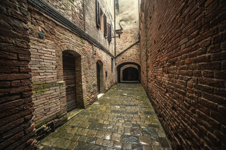 Narrow alley surrounded by stone walls in Buonconvento. Tuscany, Italyの写真素材